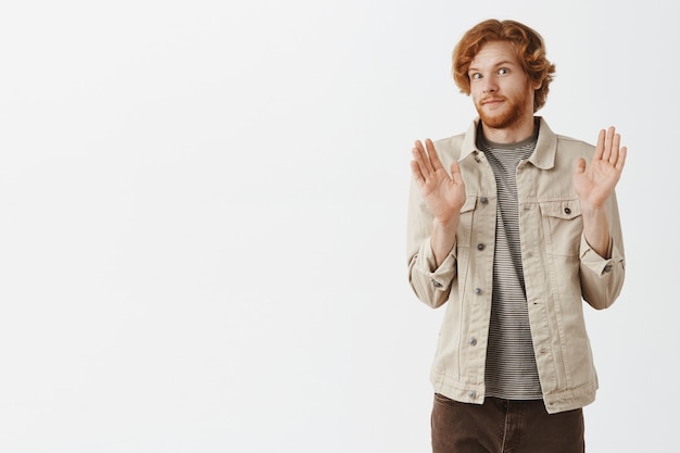 Free photo awkward bearded redhead guy posing against the white wall