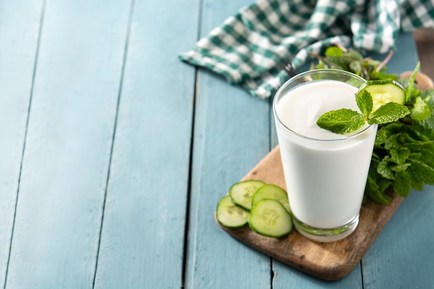 Ayran drink with mint and cucumber in glass on blue wooden table