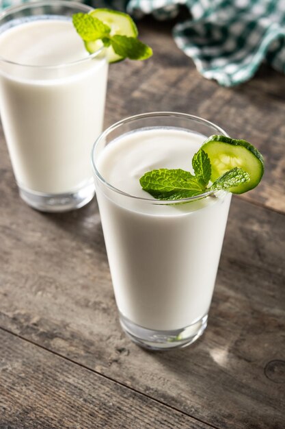 Ayran drink with mint and cucumber in glass on wooden table