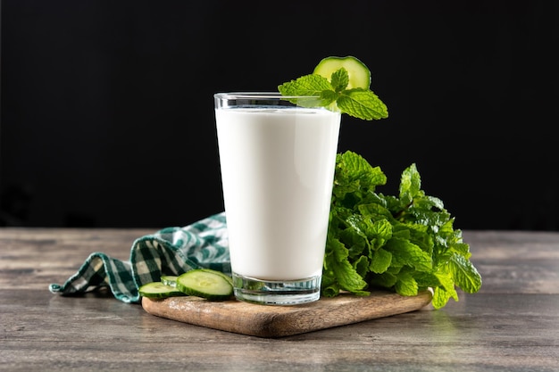 Ayran drink with mint and cucumber in glass on wooden table