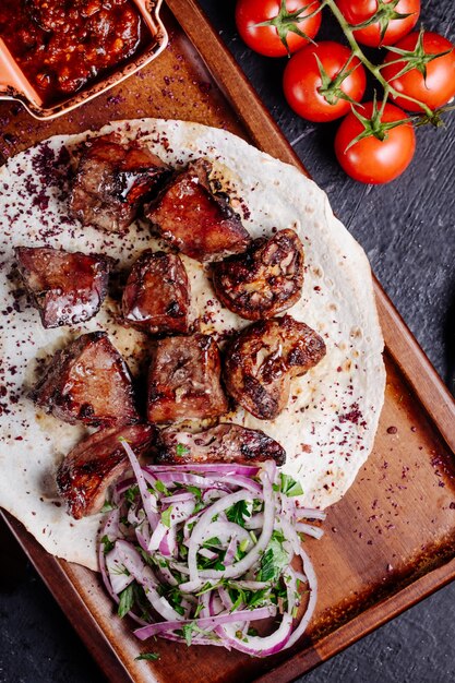 Azerbaijani beef kebab in lavash bread with onion salad and bbq sauce.