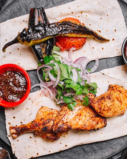 Azerbaijani chicken kebab served with grilled vegetables on flatbread