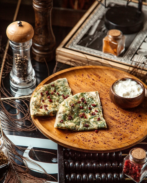 Azerbaijani gutab stuffed flatbread with herbs garnished with pomegranate seeds and yogurt