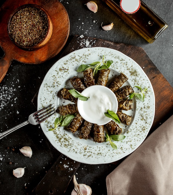 Free Photo azerbaijani long wrapped grape leaves dolma garnished with yogurt and dried mint leaves