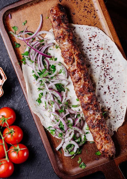 Azerbaijani lule kebab in lavash bread with onion green salad.