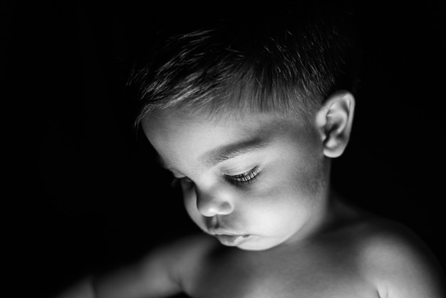 Baby boy on black background with light reflecting on his face