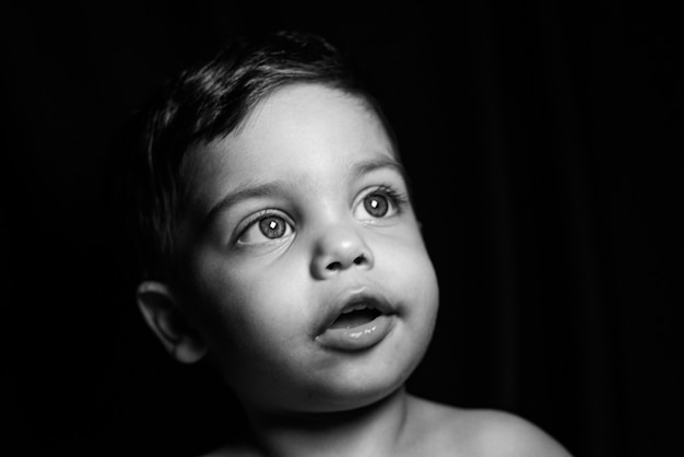 Baby boy on black background with light reflecting on his face