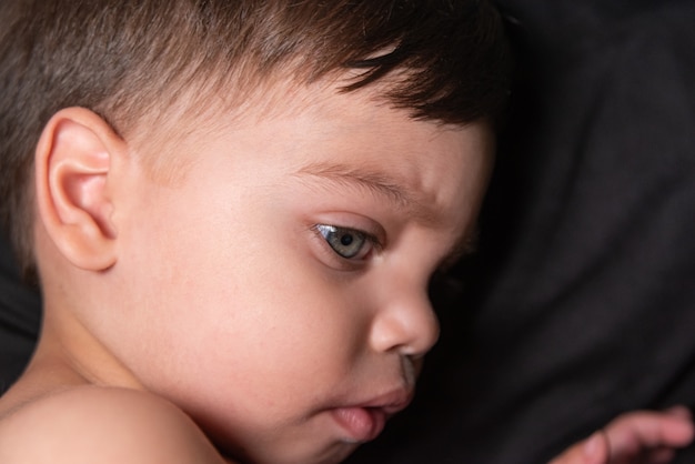 Free Photo baby boy on black fabric with light reflecting on his face