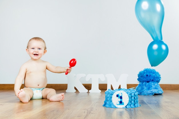 Baby boy celebrating her first birthday with gourmet cake and ba