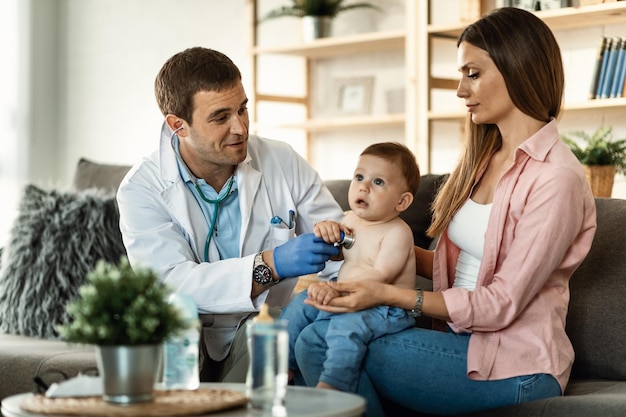 Baby boy having medical examination by male pediatrician while being with his mother Focus is on doctor