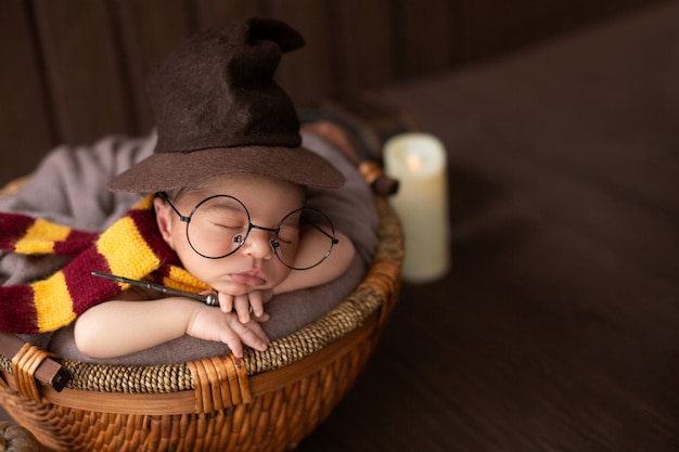 Baby boy laying inside little basket with funny wizard costume