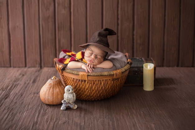 Baby boy laying inside little basket with funny wizard costume