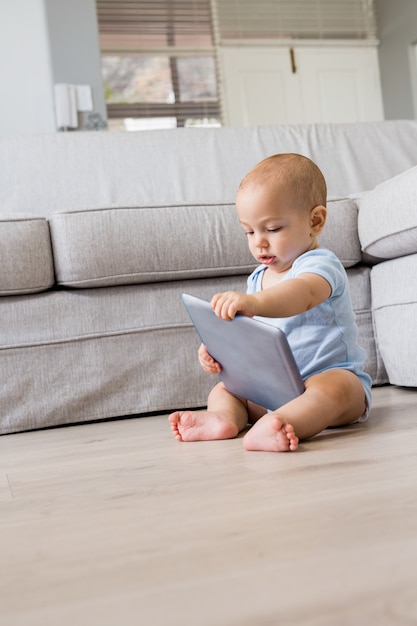 Free photo baby boy playing with digital tablet in living room