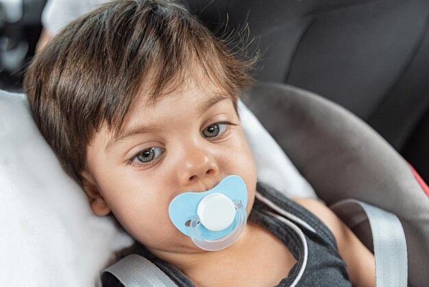 Baby boy with blue eyes sitting in the baby seat