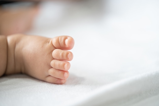 Baby feet in white bed.