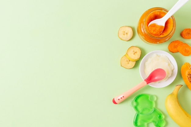 Baby food on green background above view