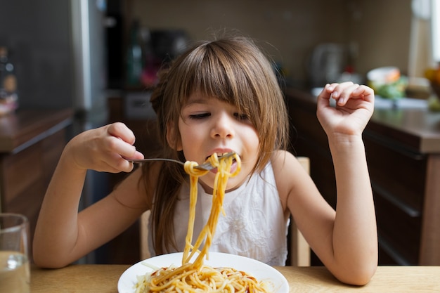 Baby girl having pasta dish indoor