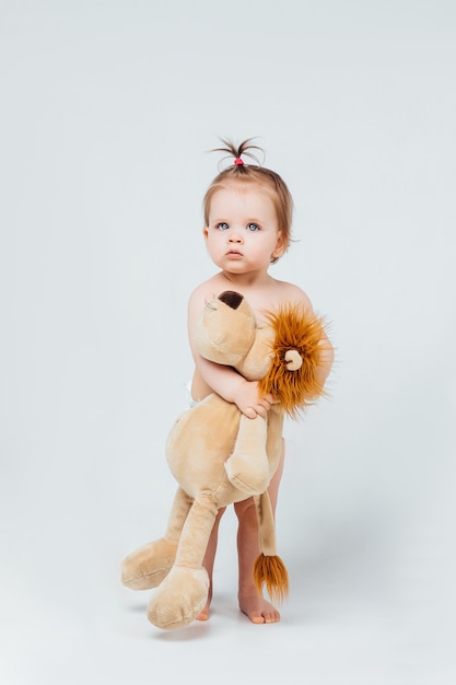 Free Photo baby girl playing with her lion toy isolated on white wall.