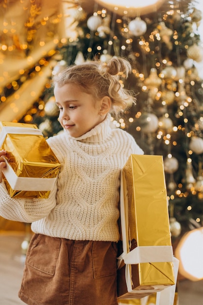 Free photo baby girl with christmas gifts under the christmas tree