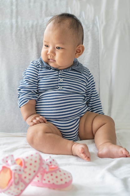 A baby learns to sit on a white bed