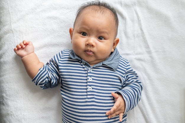 Baby lying face up on a white bed