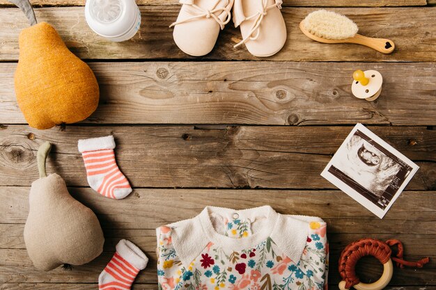 Baby's clothing and products arranged in circular shape on wooden table