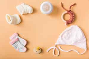 Free photo baby's sock; pair of woolen shoes; pacifier; cap; milk bottle; toy on an orange background