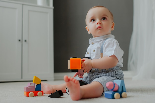 Baby sitting on the floor with toys and suprised.