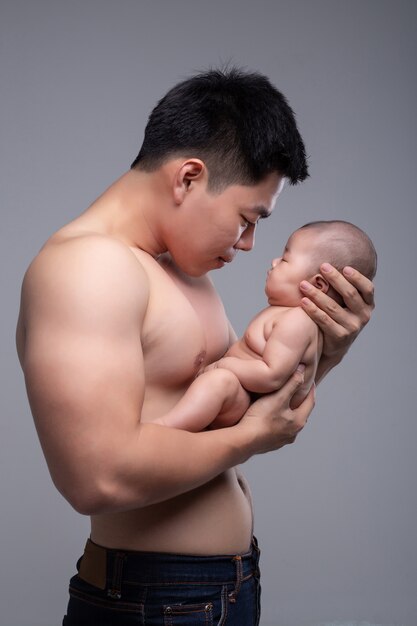 The baby sleeps in the hands of a strong father.