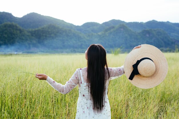 The back of a beautiful woman who is happy on the meadow with a big mountain as a .