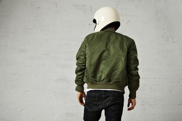 Free photo back portrait of a motorcyclist in white helmet and green bomber jacket isolated on white