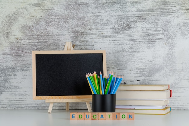 Back to school concept with blackboard, pencils, books, education text on wooden cubes on white