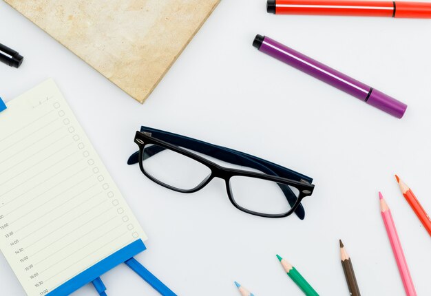 Back to school concept with glasses, school supplies, daily planner on white table flat lay.