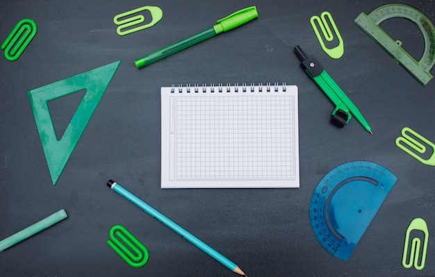 Back to school concept with notebook, pen, pencil, chalk, compass, paper clips, rulers on grey background flat lay.