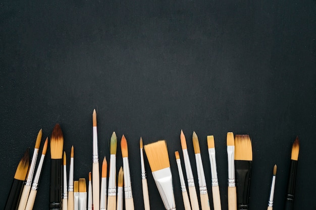 Free photo back to school concept with paint brushes on dark surface