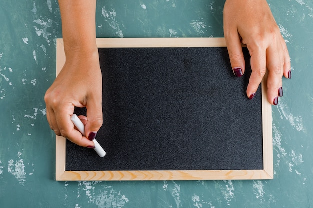 Free photo back to school concept. woman writing on blackboard with chalk.