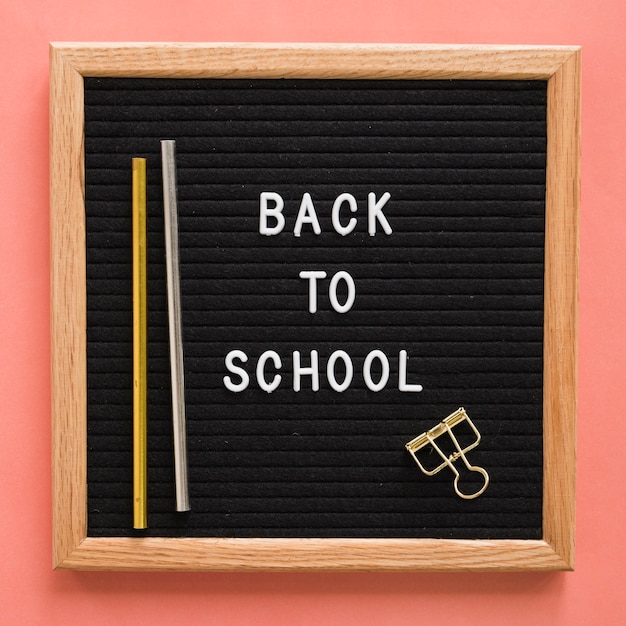 Free photo back to school text on slate with pencils and bulldog clip on colorful backdrop