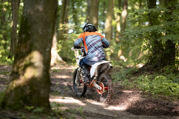 Back view active man riding motorbike in the forrest