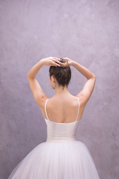 Back view ballerina fixing bun hairstyle