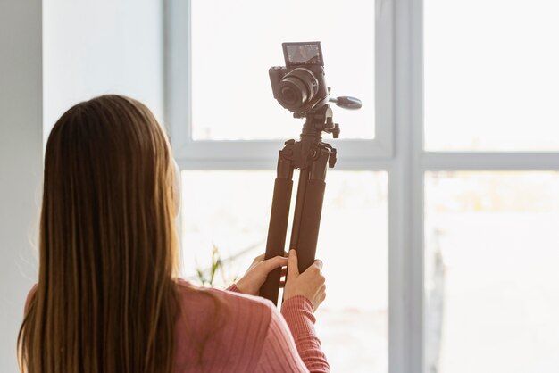 Back view blogger holding tripod up with camera