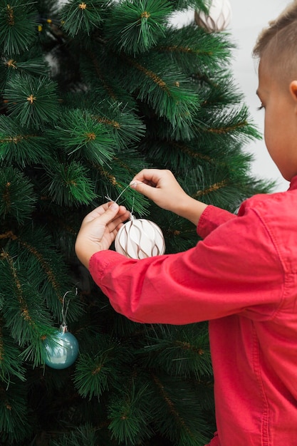 Free photo back view of boy decorating christmas tree