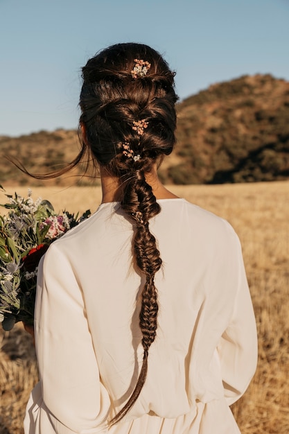 Free photo back view bride holding flowers bouquet