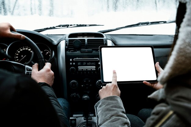 Back view of couple in the car consulting tablet while on a road trip