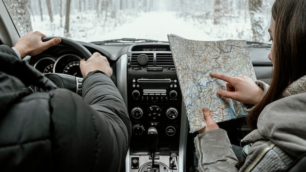 Back view of couple in the car while on a road trip consulting map