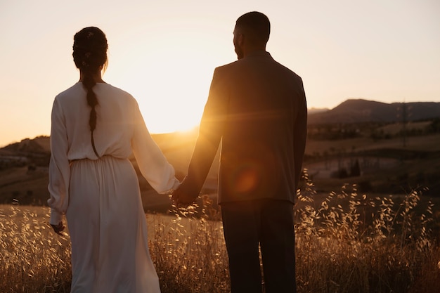 Back view couple holding hands outdoors