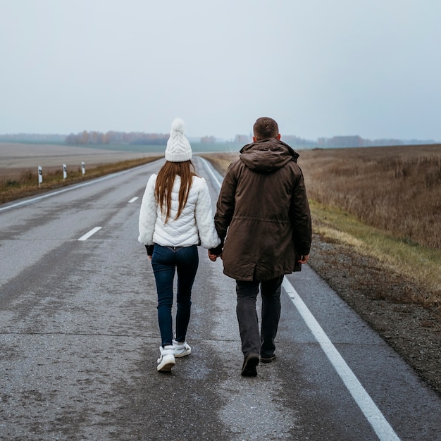 Back view of couple holding hands on the road