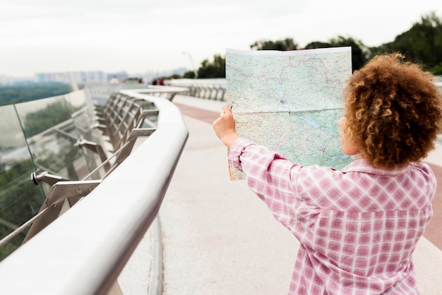 Free Photo back view curly woman checking a map