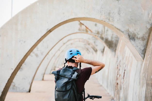 Free photo back view of a cyclist putting on his helmet