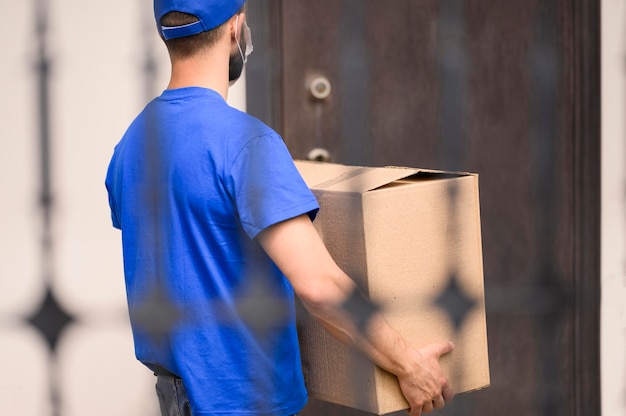 Back view delivery man carrying shipment