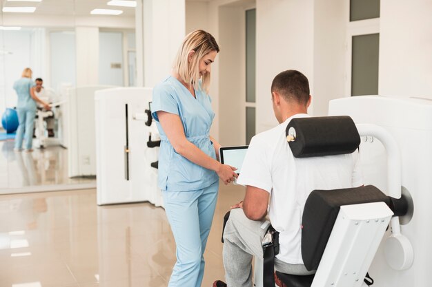 Back view doctor helping patient with a medical exercised